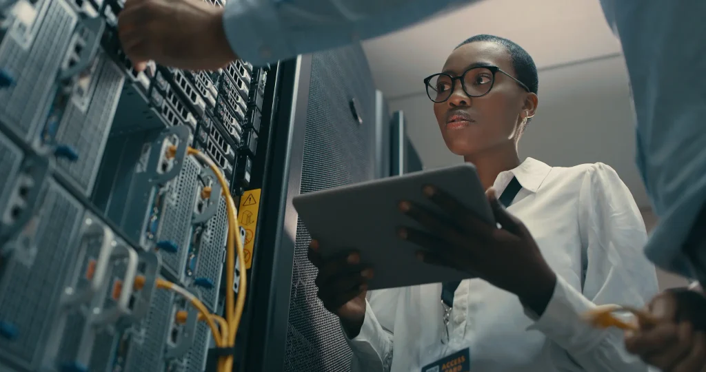 IT woman in a server room looking at a tablet.