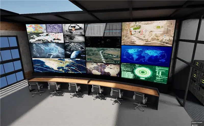 A large wall of multiple monitors displaying maps, data, and satellite imagery in a dark control room with a desk and six office chairs.